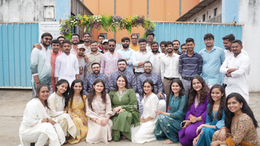 The team at the Suryon Industries factory gate under a flower arch